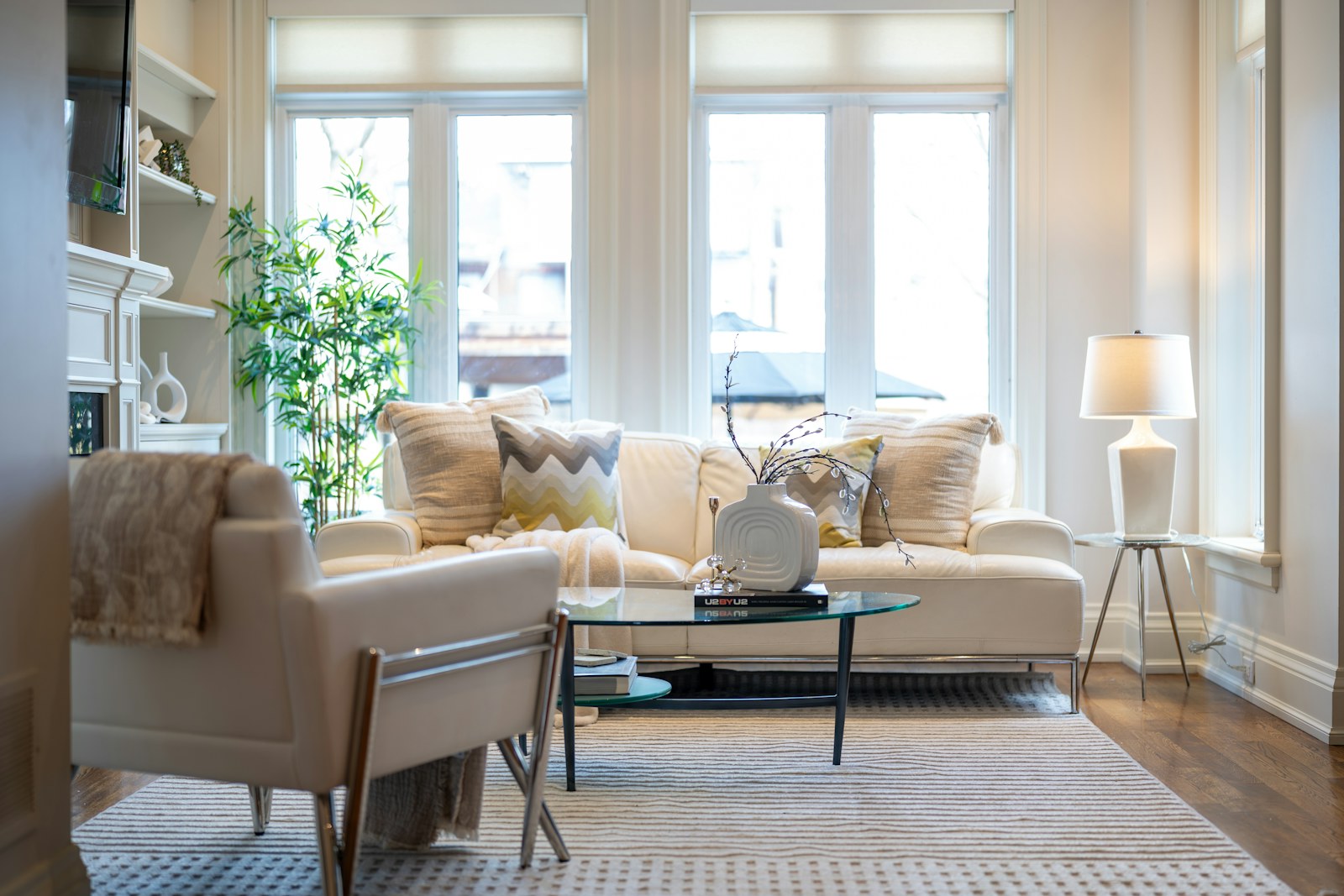 A cream-toned living room with a sofa, armchair, and pale wood flooring