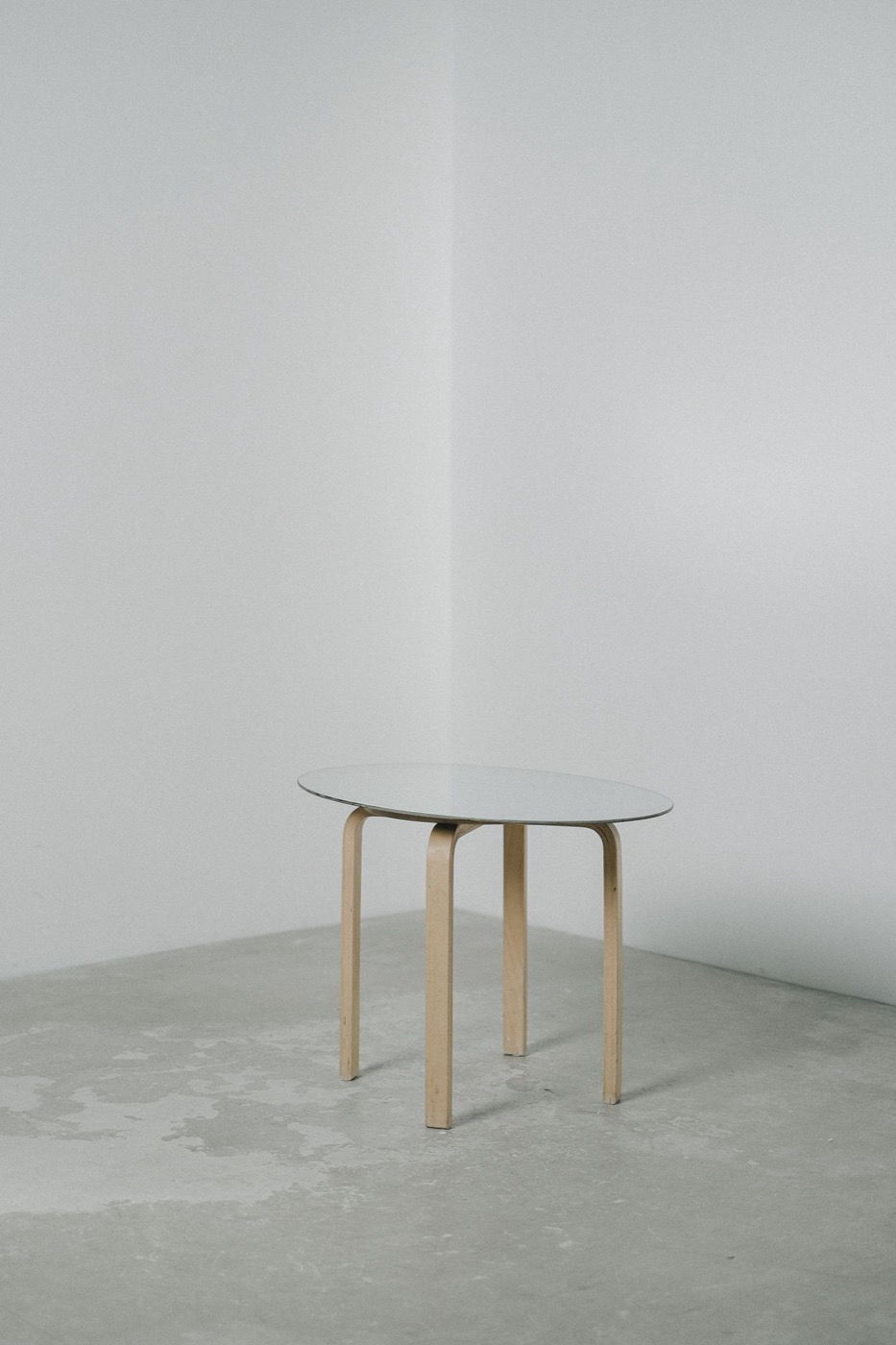A small round white side table with three bentwood legs in a light room.